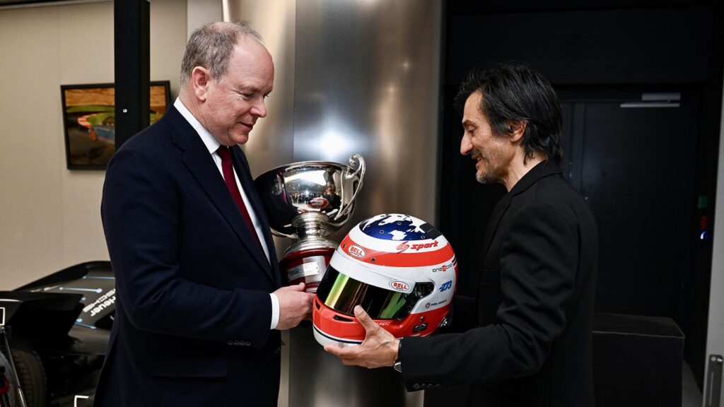 Two men talking one is holding a racing helmet
