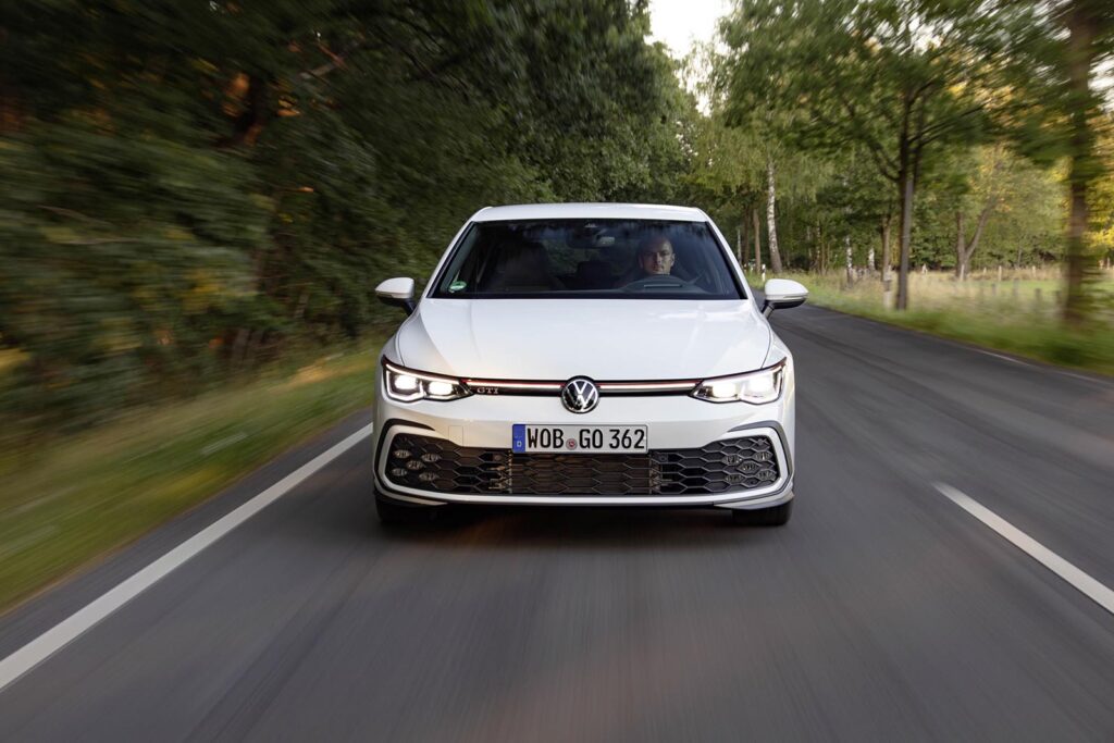 white VW GTI on road with trees background