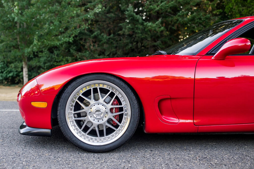red rx7 with aftermarket wheels parked on street