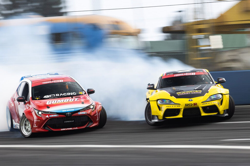 corolla and supra drifting on racetrack