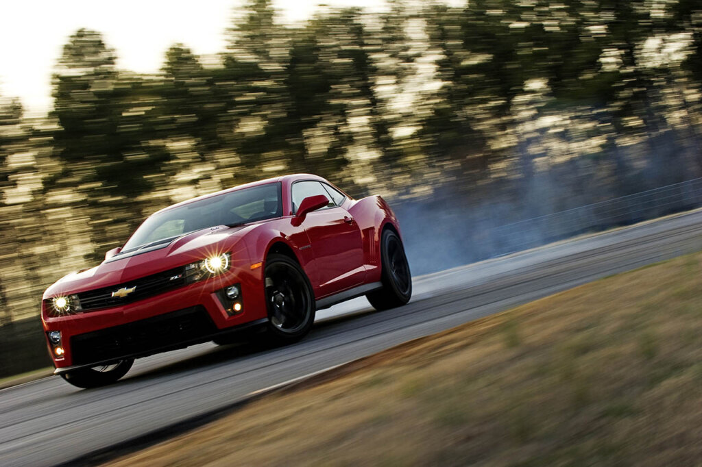 red 2013 chevy camaro drifting on a racetrack