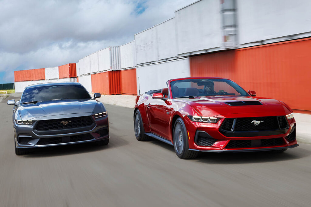 black and red seventh gen mustang next to cargo containers