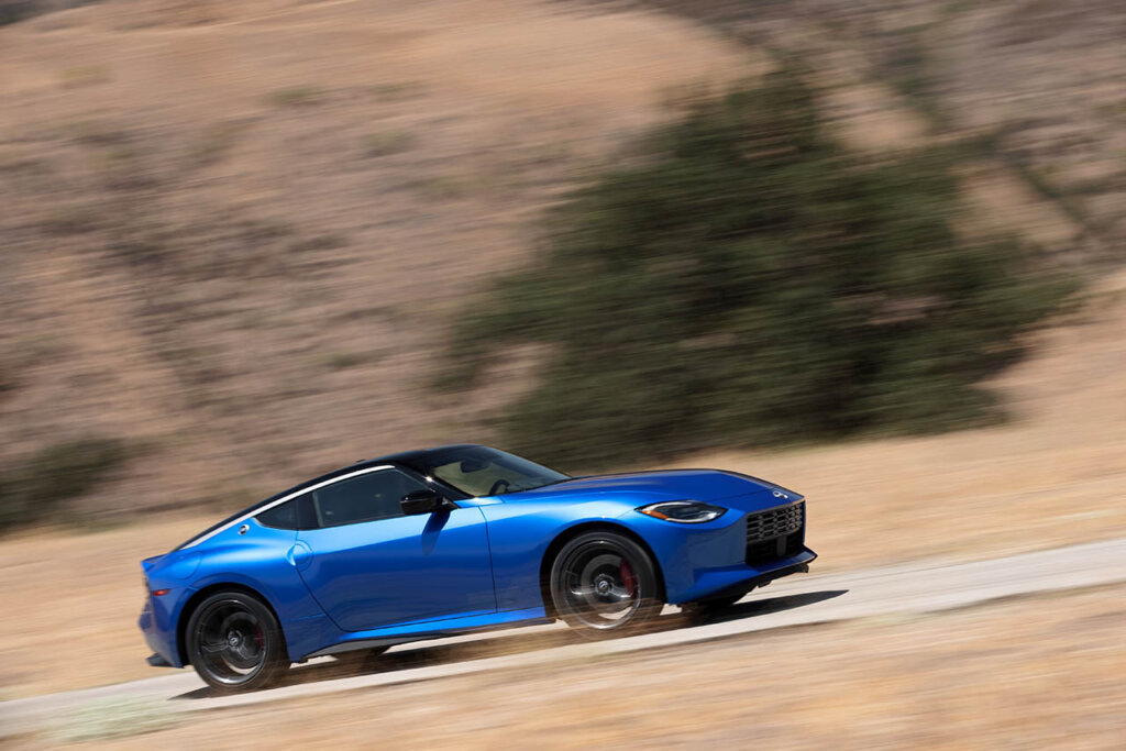 blue nissan z speeding on a dirt road