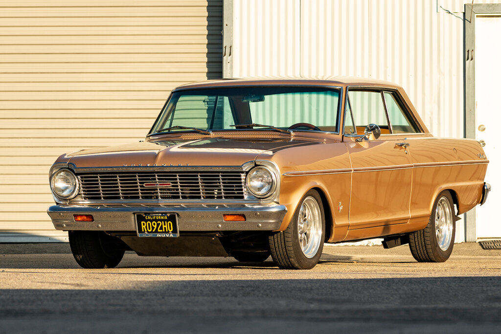 1965 gold chevy nova next to a garage