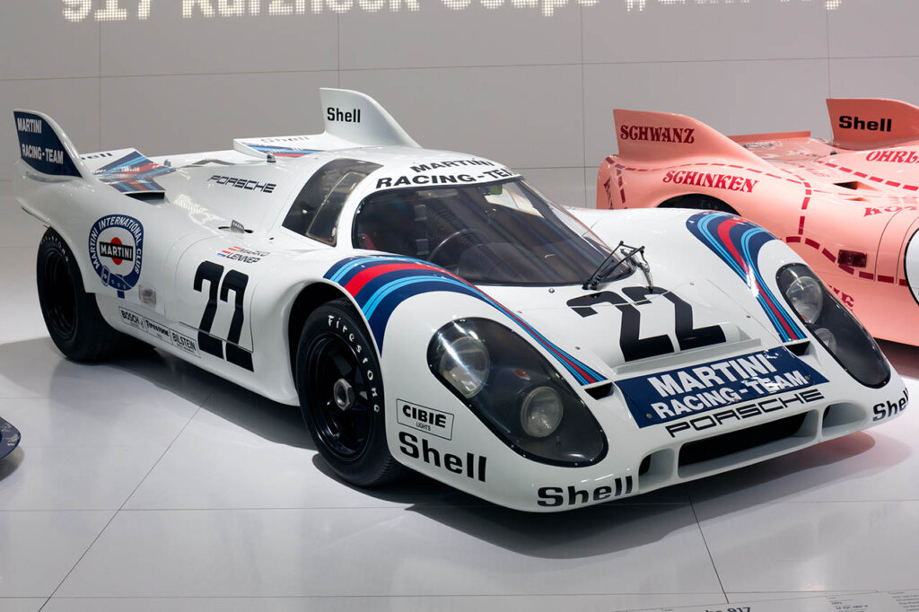 a white porsche with Martini blue and red racing stripes in a display room