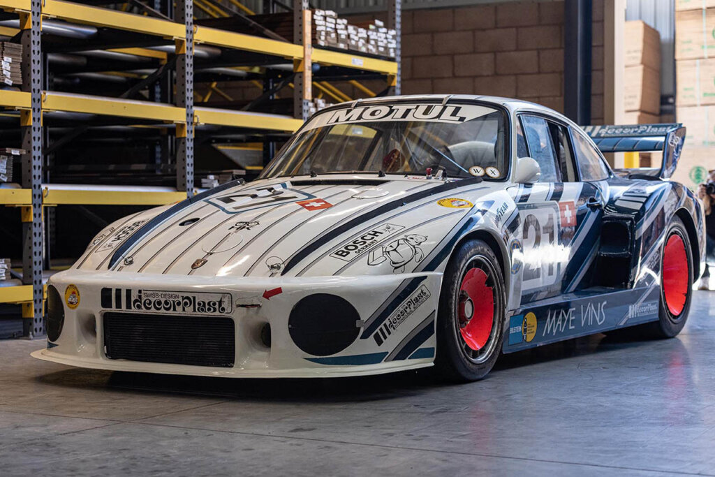 A red/blue/white Porsche 935 in a warehouse