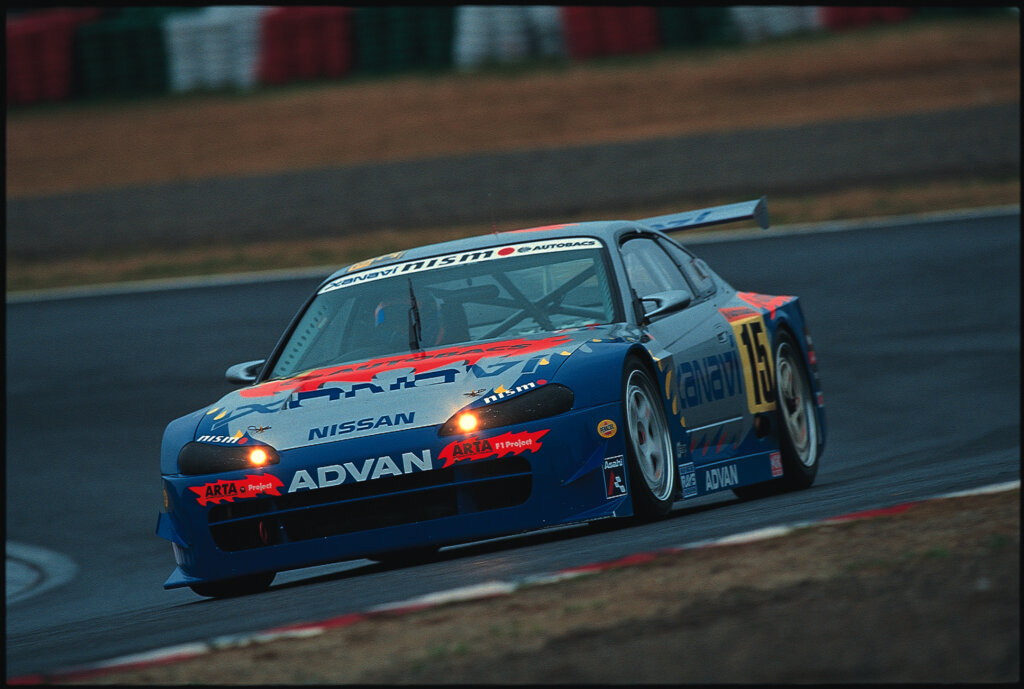blue nissan skyline (r34) racing on wet track