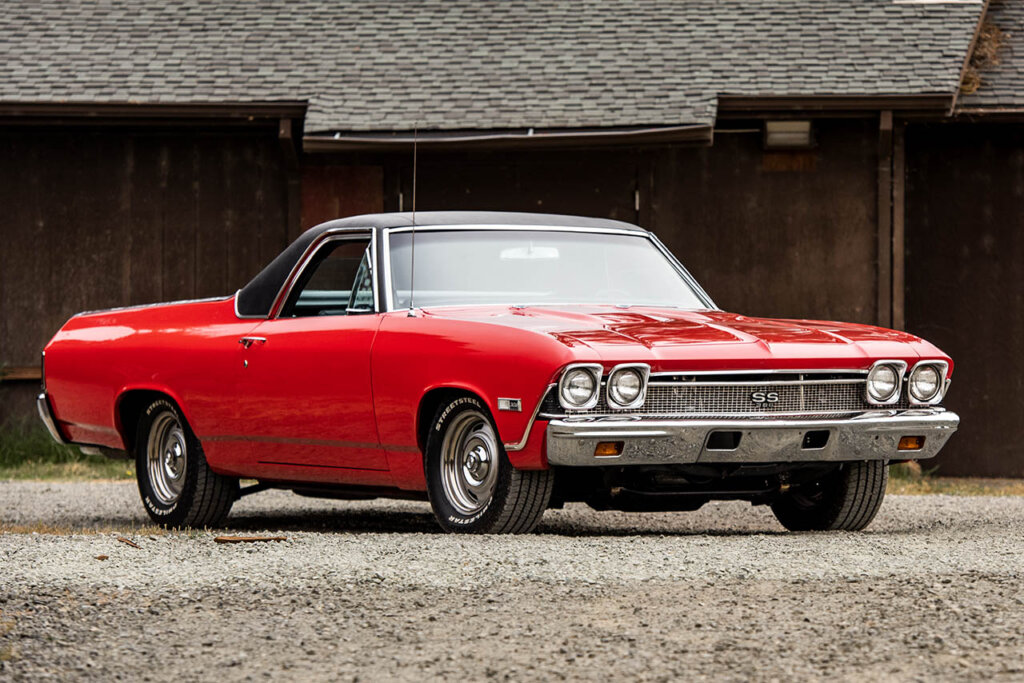 red 68 el camino next to a barn