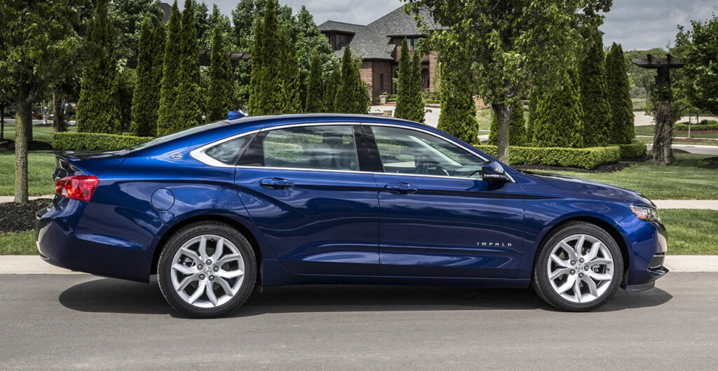 blue 2018 Chevrolet Impala next to houses