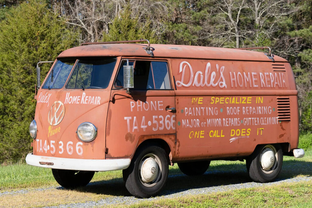 Rusty old VW van parked on grass, with business name painted on the side of it
