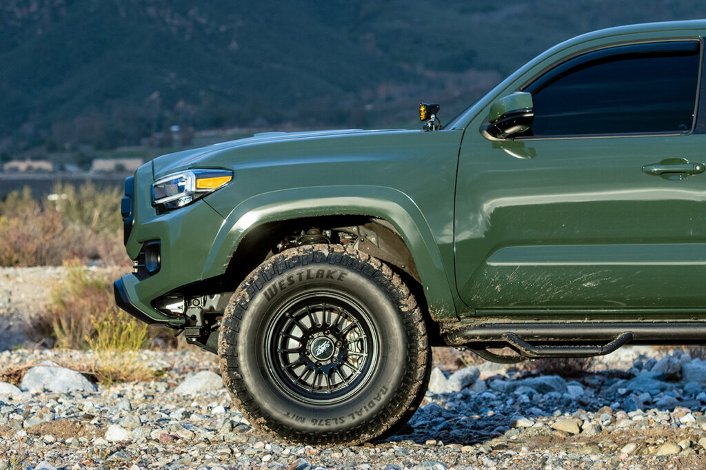 Black Rhino Wheels setup on a green Toyota tacoma, rocks everywhere and mountains behind them