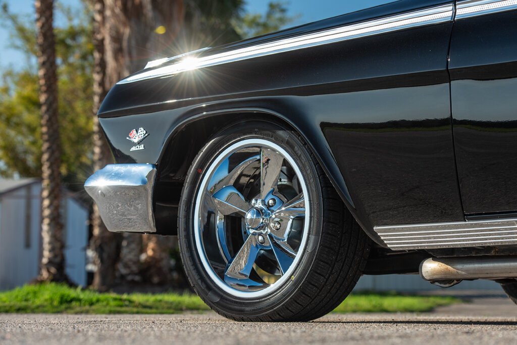 Cast 5 spoke wheel on a black chevy impala, light flare hitting the fender