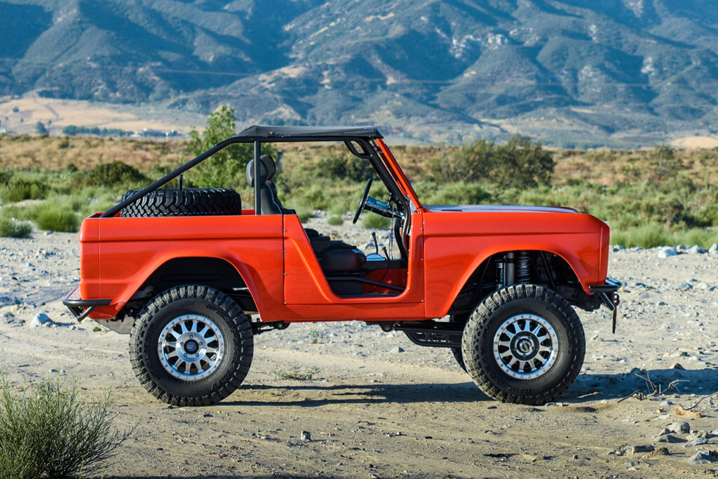 Orange Jeep with cast Method Wheels, car parked on dirt road and mountains behind the car