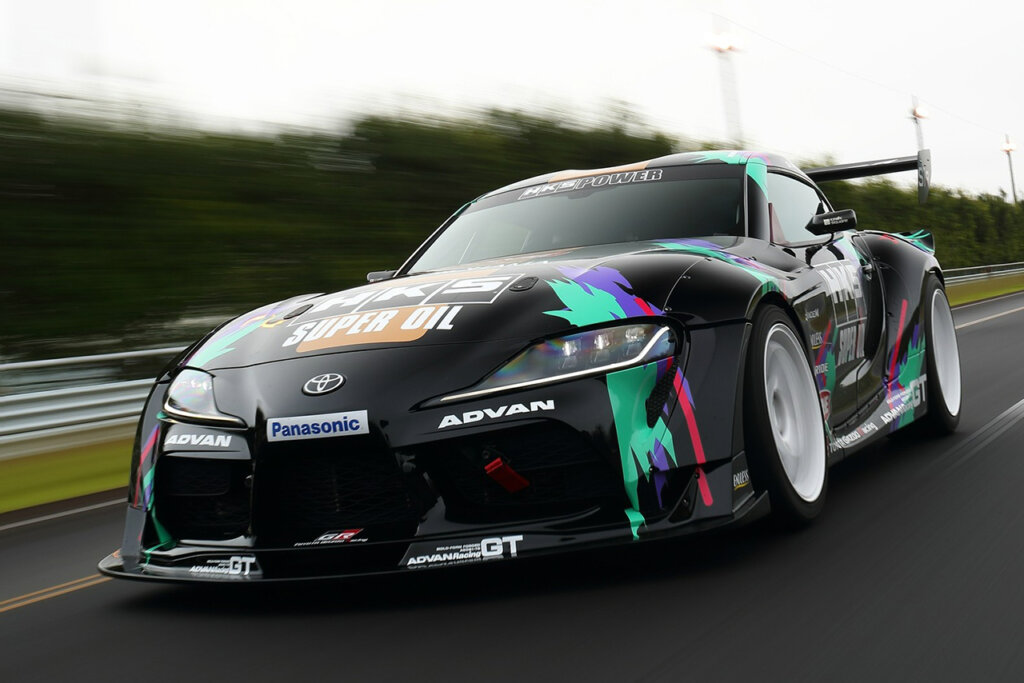 black Toyota Supra with racing livery driving fast on the road