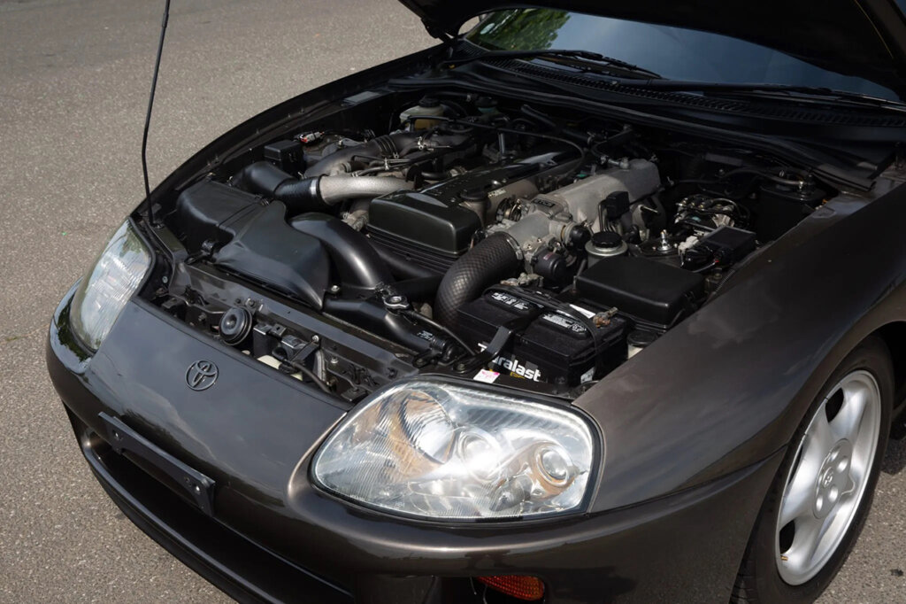 dark brown supra with 2JZ engine showing and hood propped open