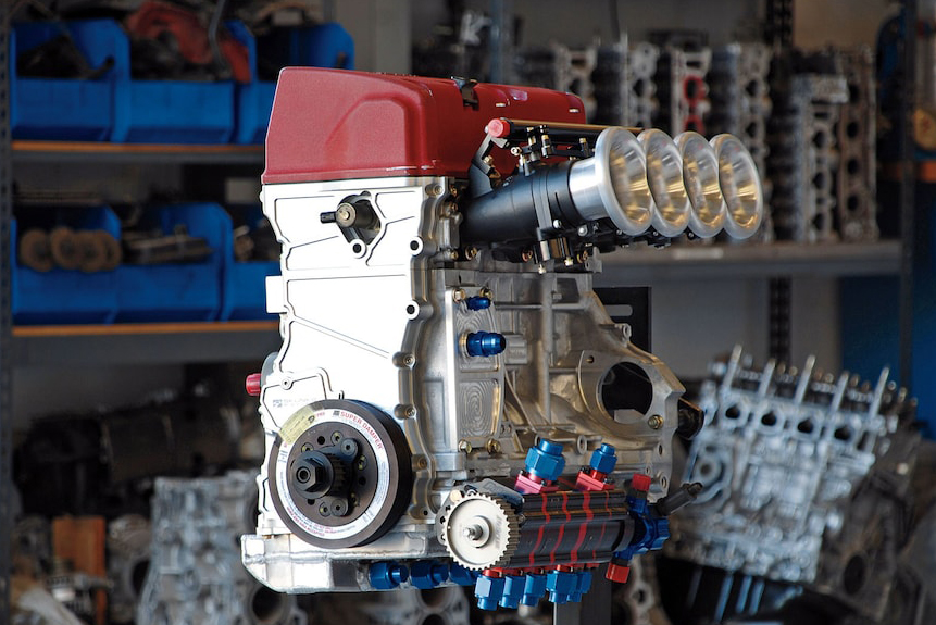 K20 engine on engine stands in a garage surrounded by other engine blocks in background