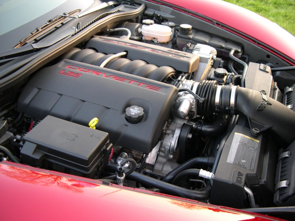 LS2 engine connected to tubes and other engine parts in a red c6 vehicle