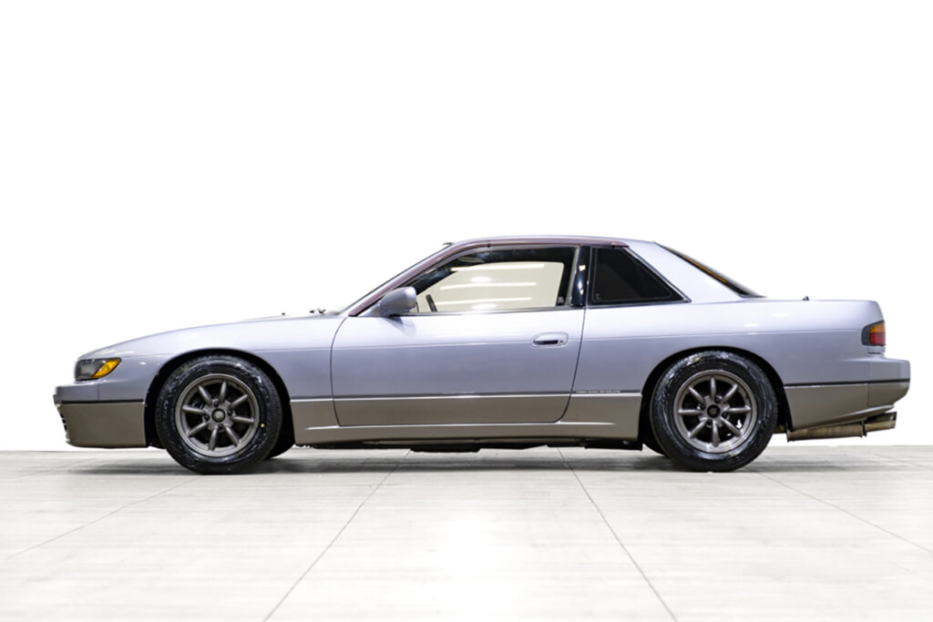 side shot of a two tone Silvia s13 in front of a white wall