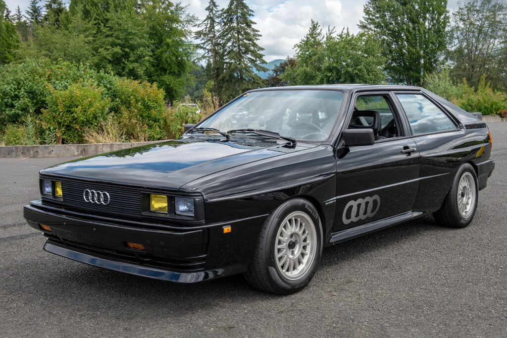 Black Audi Quattro A1 parked with green trees behind it