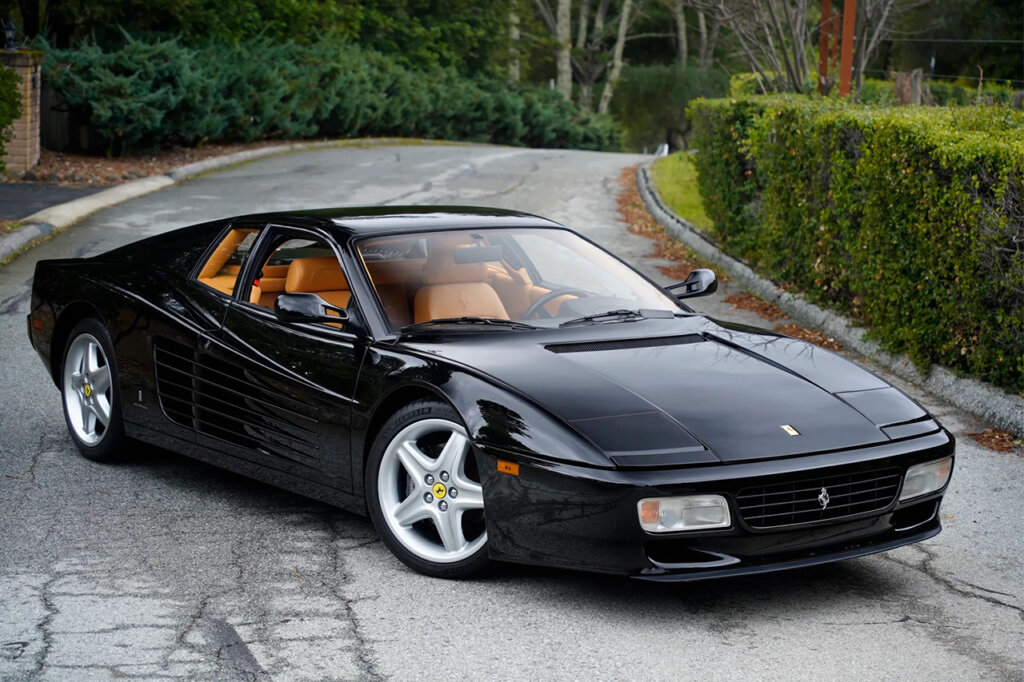 Black 512TR parked in a driveway diagonally with bushes on the side of it