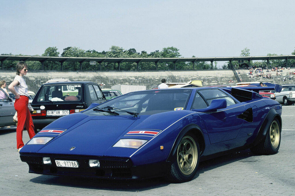 woman next to a blue lambo countach