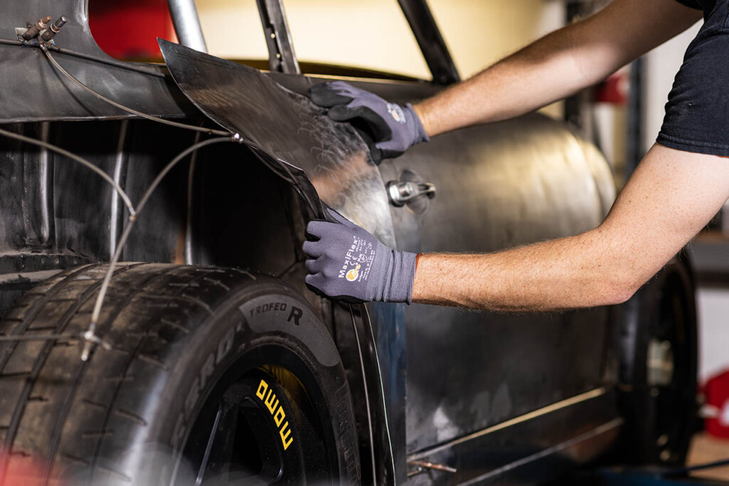 emory motorsports worker applying sheet of metal on porsche 356