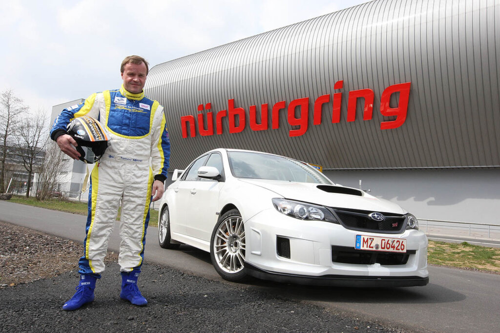 tommi makinen next to a subaru rally car
