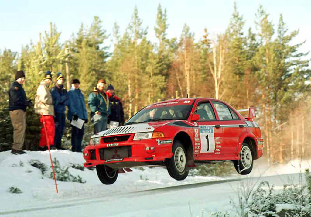 Tommi Mäkinen in a red mitsubishi lancer evo in the snow