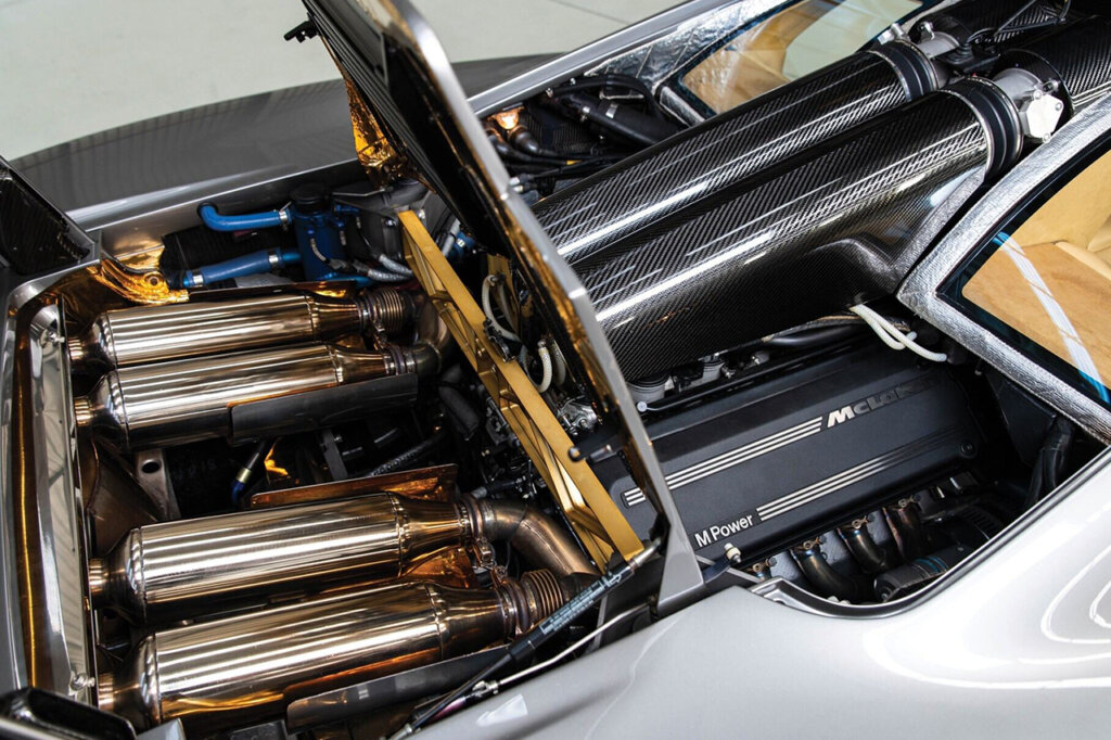Rear engine with big metal cylinders going toward the rear of the McLaren F1