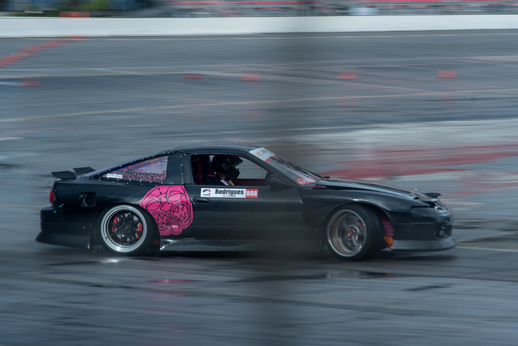 Black and pink Nissan S13 hatch drifting through a turn