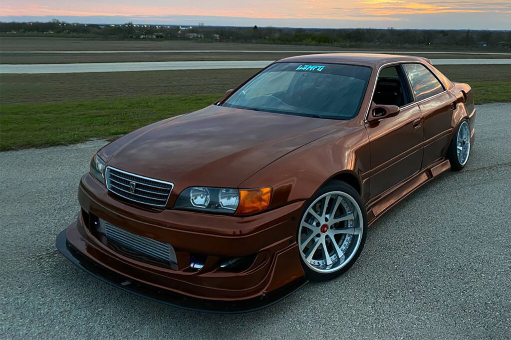 Orange Toyota Chaser parked at an angle with the sunset behind the car