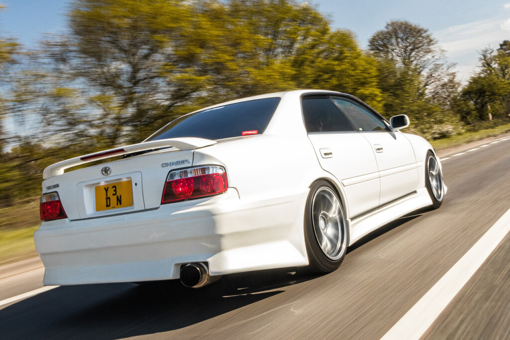 White Toyota Chaser driving on a street fast passing trees