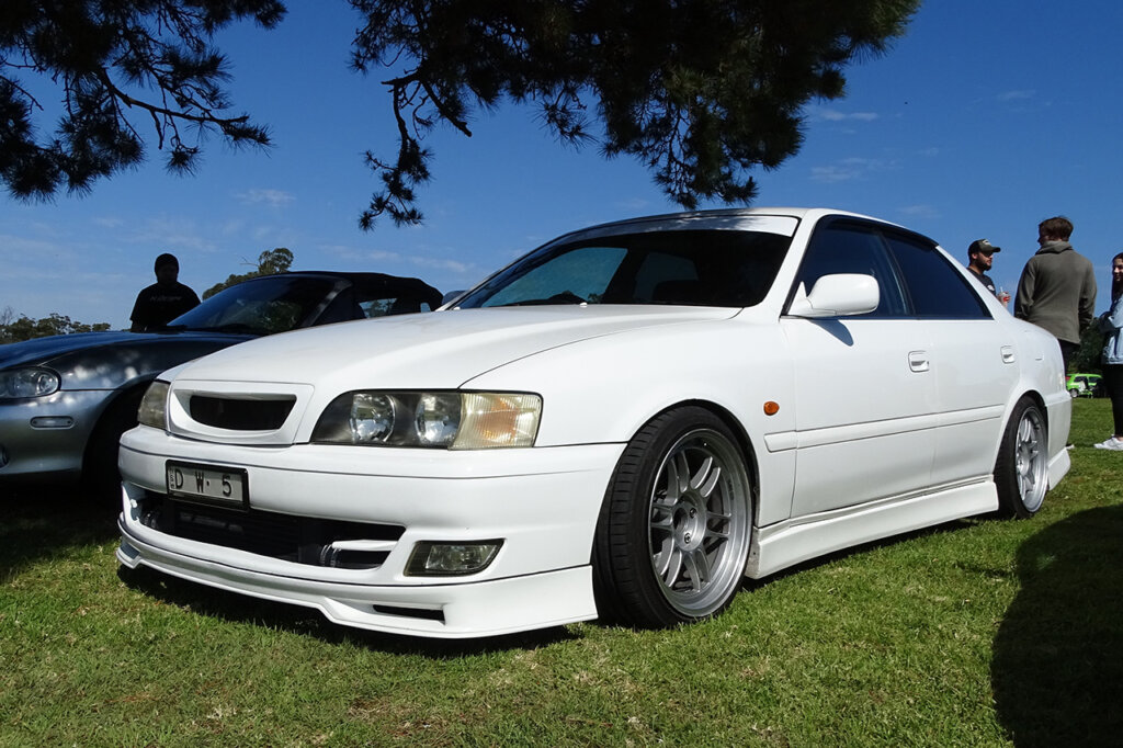 White Toyota Chaser parked under a tree on grass