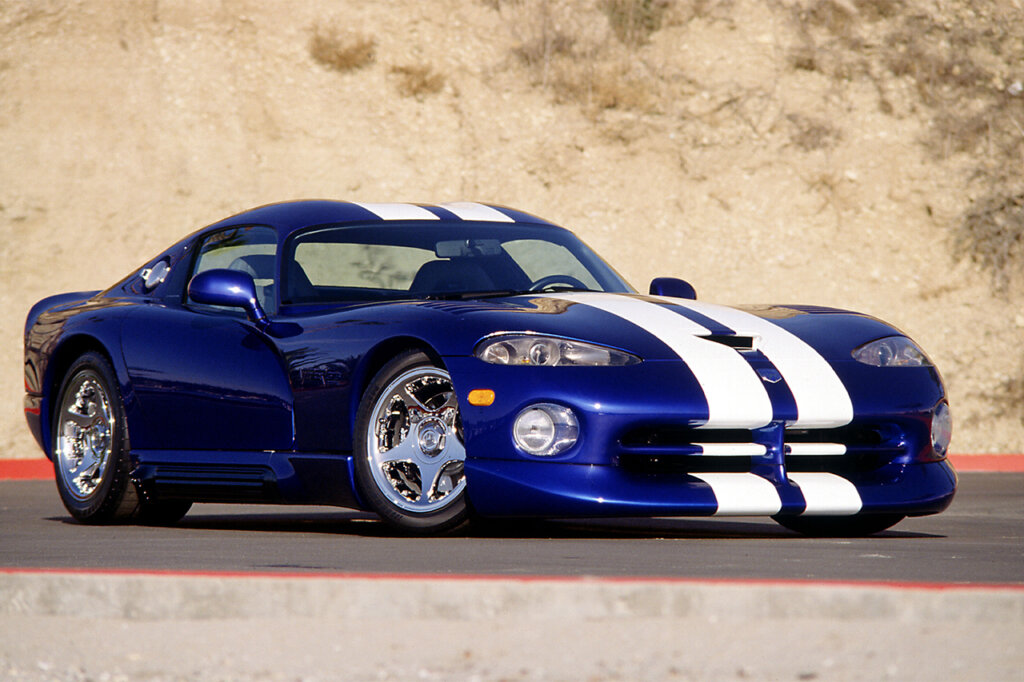 Blue Dodge Viper with white racing stripes parked in front of a hill