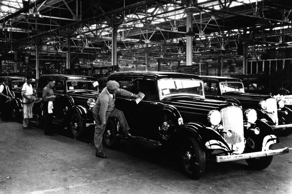 black and white photo of a man wiping down a Dodge Touring car in a warehouse