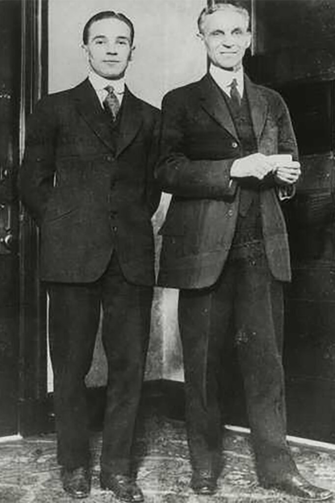 black and white photo of two men in suits standing next to one another