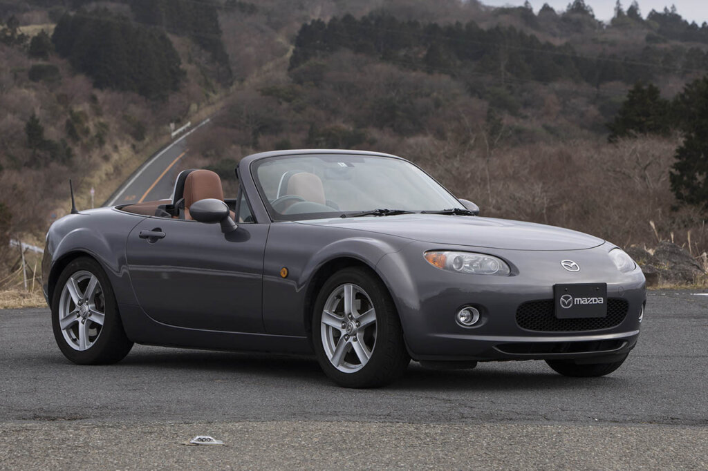 grey mazda mx5 next to rocky mountains