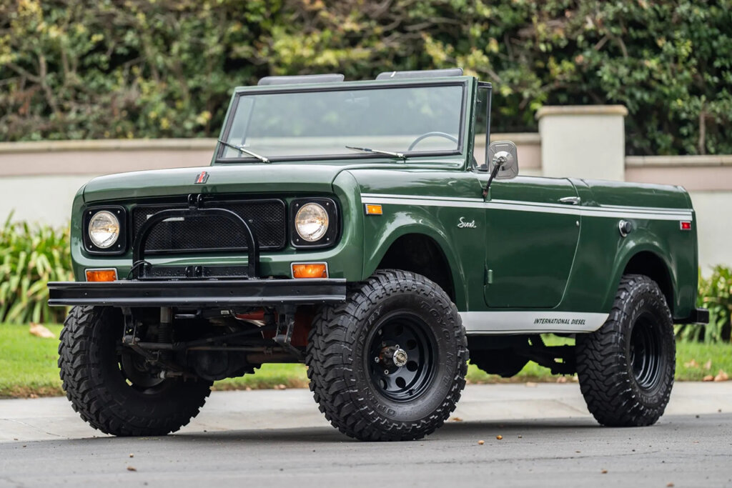 Green Scout 800 truck parked in front of a yard with trees and a fence behind it