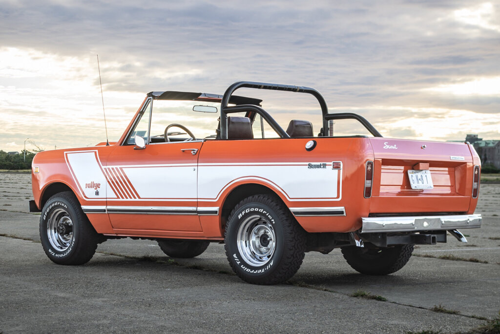 Orange and white Scout II parked on a road with clouds in the sky
