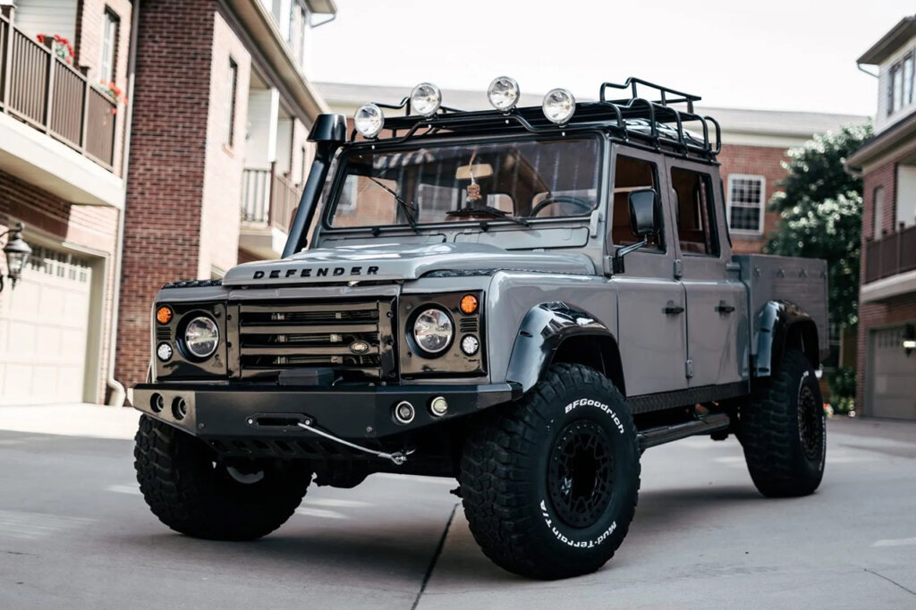 Grey Land Rover 130 Parked in a drive way surrounded by homes