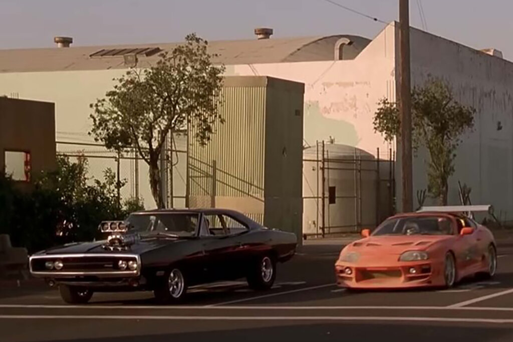 Two Cars a Dodge Challenger and an Orange Toyota Supra at a stop next to eachother
