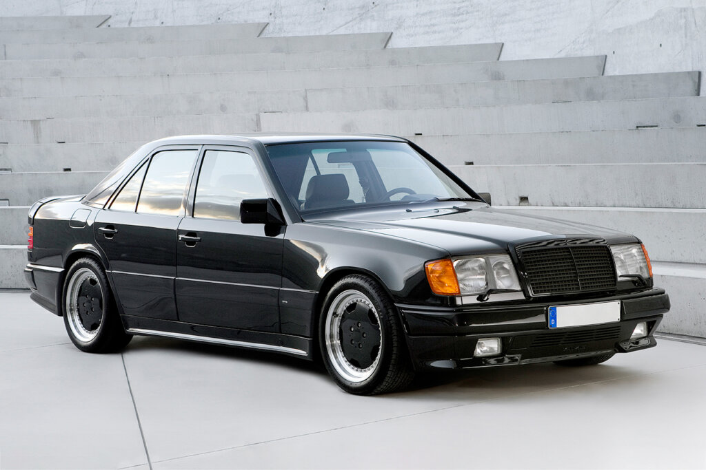 Black AMG 300E parked next to a building wall