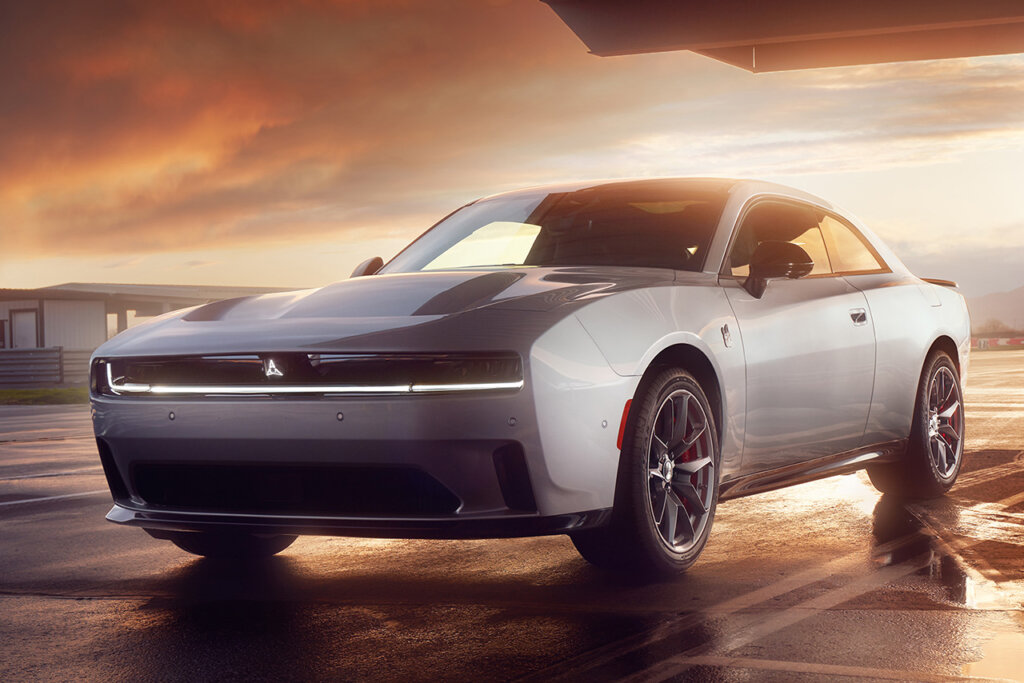Silver Dodge Charger EV with sunset background behind it