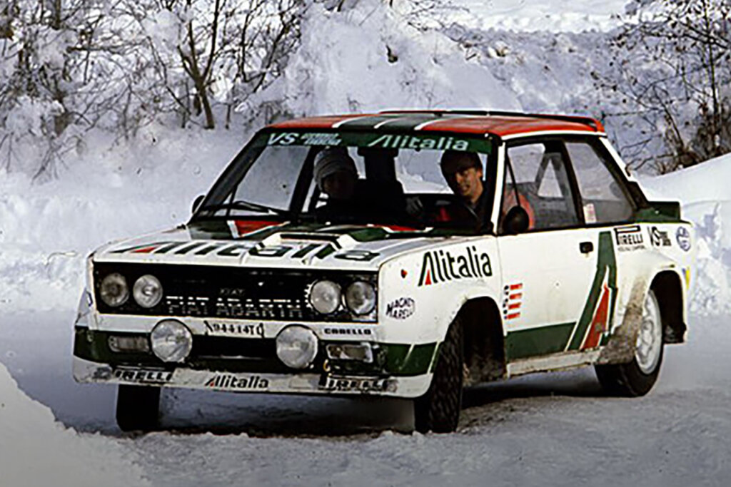 White Fiat Abarth 131 rally car drifting through a snow turn