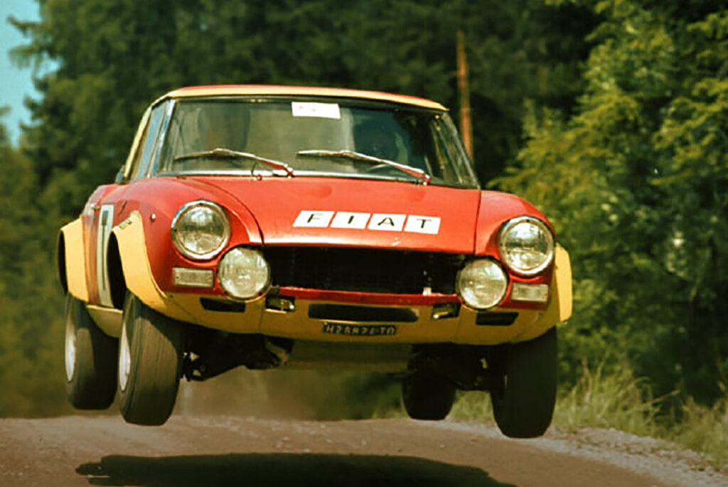 Red and yellow Fiat Abarth 124 rally car flying through the air