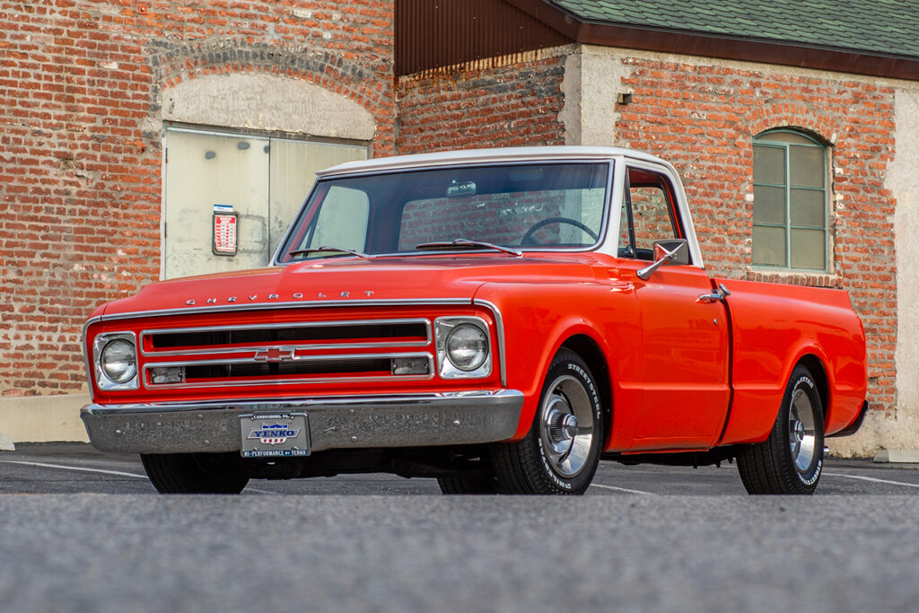 Orange and white roof Chevy C10 parked in front of a brick wall