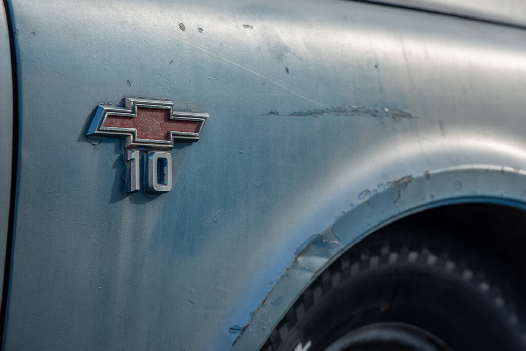Blue fender of a chevy C10 with a worn out red chevy badge