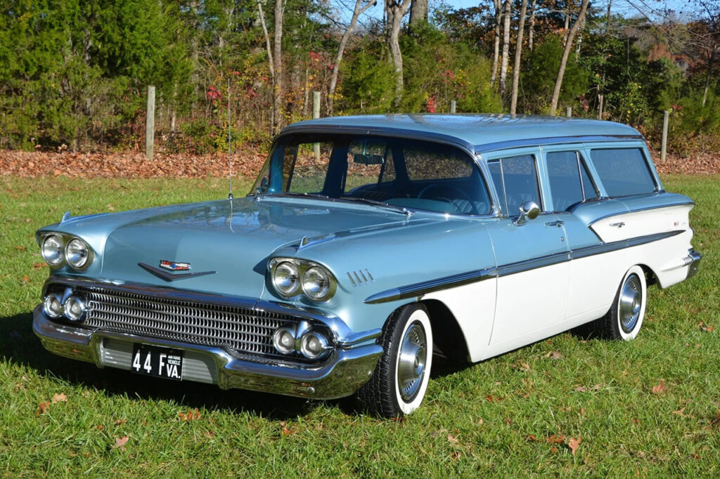 Blue and white 2nd gen Chevy Nomad with grass and trees in background