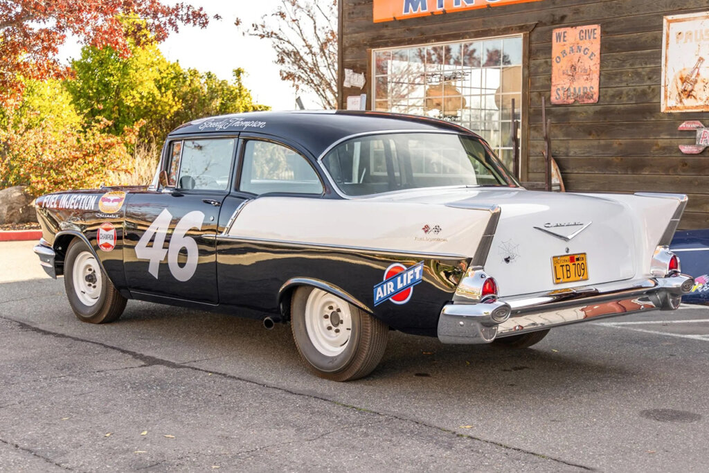 Rear shot of a black and white Chevy Nomad race car in front of a Brown wood paneled wall