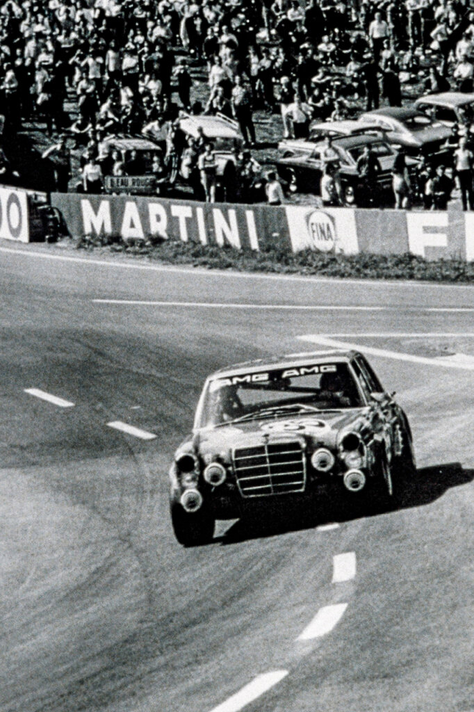 black and white photo of race car Red Pig on a track with spectators behind it